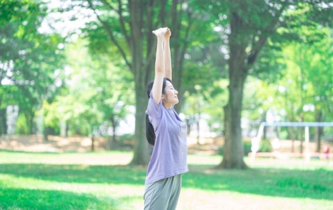公園で気持ちよく深呼吸をしている女性