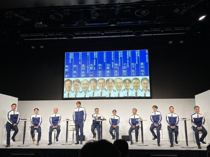 責任者がずらりと並ぶ 後ろのモニターは「競馬の出走のようだ」との声も