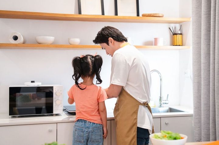 幼い娘と料理をする父親