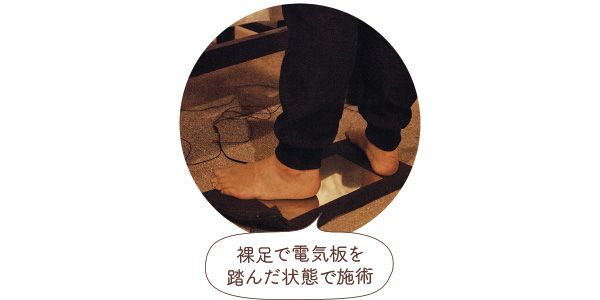 裸足で電気板を踏んだ状態で施術