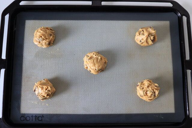 天板にオーブンシートを敷き、スプーンを2つ使って間隔を大きく空けて生地を腰高に乗せる。