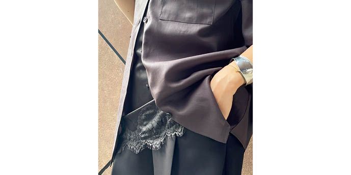 裾のボタンを開けて、インナーのレースを覗かせて華やかさをプラス。パンツと同じ黒を選んでさりげなく上品にコーディネイト。