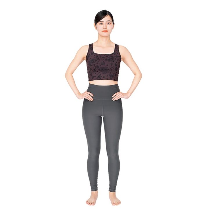 足を骨盤幅程度に開いて立つ。両手は腰に軽く添えて、肩の力は抜いてリラックス。