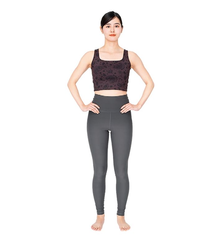 足を骨盤幅程度に開いて立つ。両手は腰に軽く添えて、肩の力は抜いてリラックス。