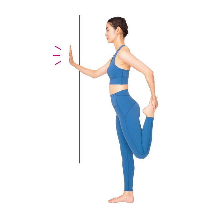 大腿のストレッチと片足スクワット。壁に右手をつき、左手で左足のつま先を持って太ももの前を伸ばす。