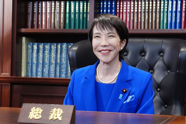 自民党総裁室の椅子に座り、笑顔を見せる高市早苗新総裁（2025年10月、時事）