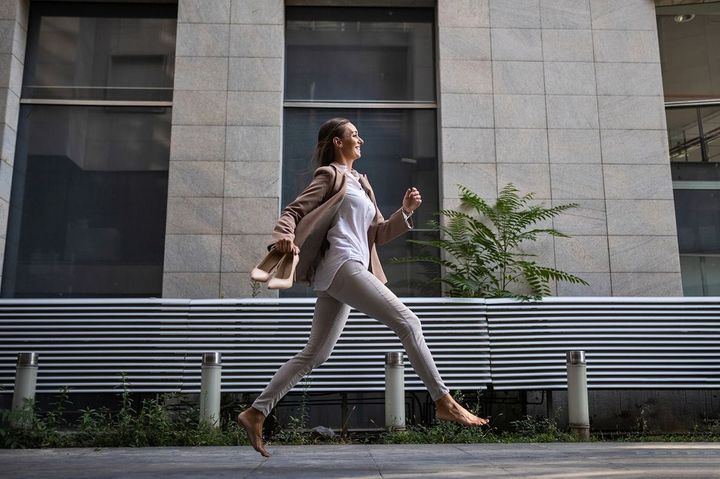 脱いだ靴を持って走る女性