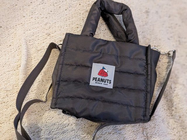バッグ背面のPEANUTSタグ。赤いダウンジャケット姿のスヌーピーがワンポイント