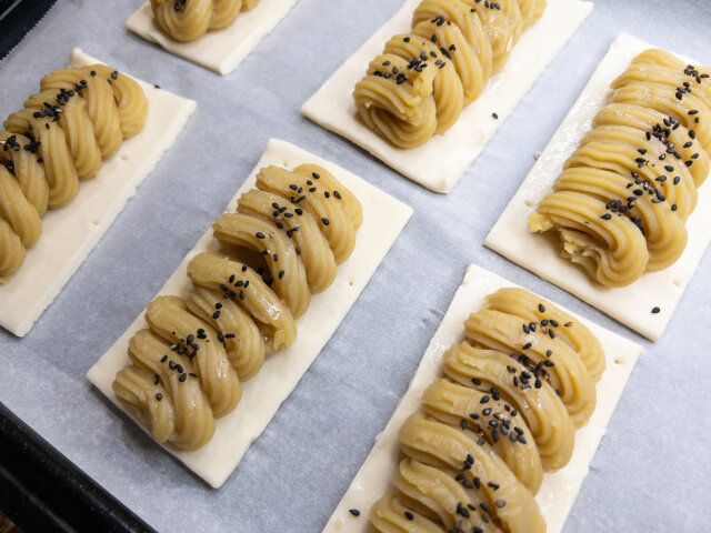 スイートポテトと冷凍パイシートに、刷毛で卵白を塗り、黒いりごまを振ります。