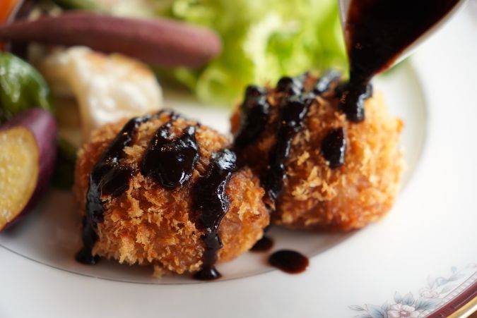 シークレットレストランK ジビエのメンチカツ 自家製ウスターソースをかけるシーン