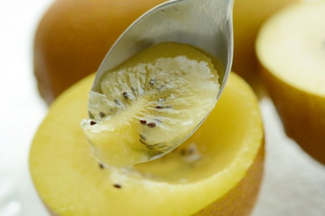 ゴールドキウイをスプーンですくう様子