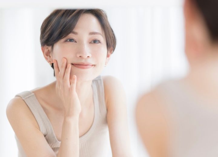鏡で顔を確認して笑顔になる女性