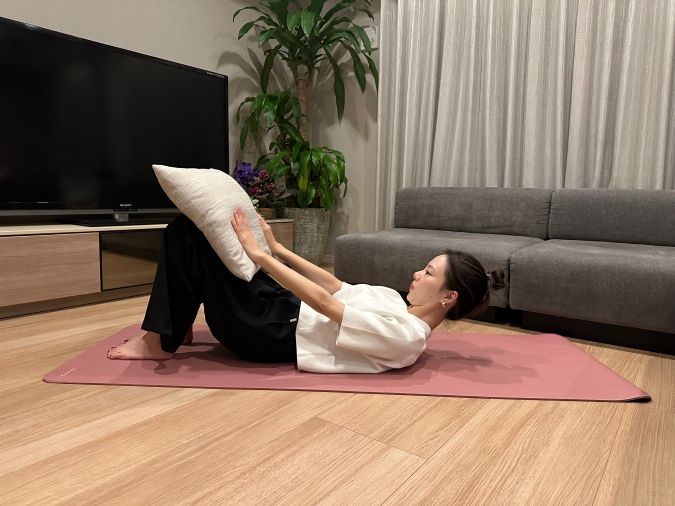 両手でクッションを軽く押し、息を吐きながら、少しだけ頭を持ち上げる。（首〜肩が床から浮くくらい）