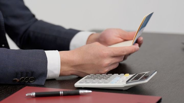 通帳を見て計算するビジネスマン