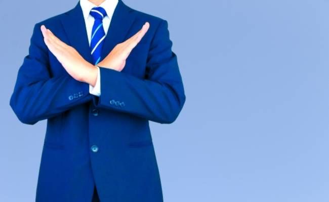 胸の前でバツマークを作るサラリーマンのイメージ