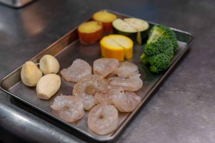 バットの上に並べられた食材（ニンニク えび ブロッコリー ズッキーニ なす さつまいも） 