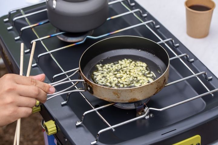 キャンプ場で調理する人 キャンプ飯 アヒージョ にんにく料理