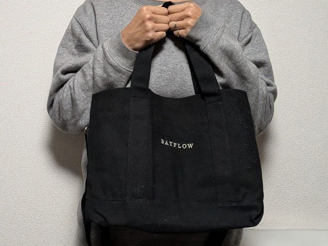 BAYFLOWの黒トートを手持ちしている正面カット。マチがしっかりありスクエア気味のフォルム