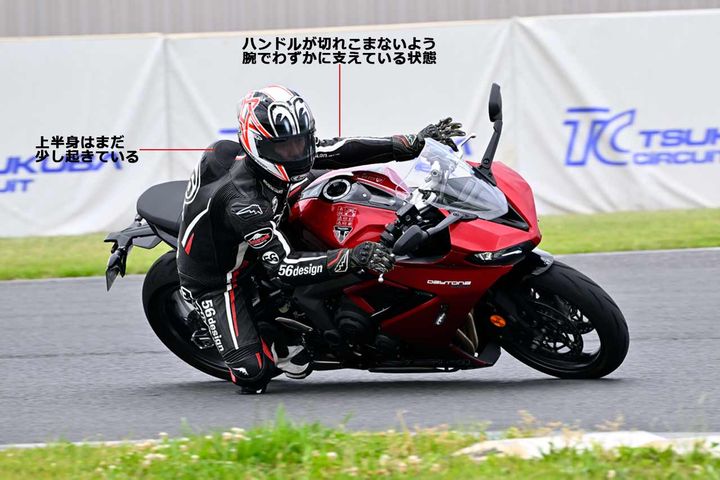 【ブレーキを解除しつつもフォークを縮ませたままのイメージ】バンク角が深くなるにつれ、減速方向に使えるタイヤグリップは減るのでフロントブレーキを緩めるが、遠心力によりフォークはある程度縮んだ状態をキープできる。これができるかどうかで、曲がり方は変わる 