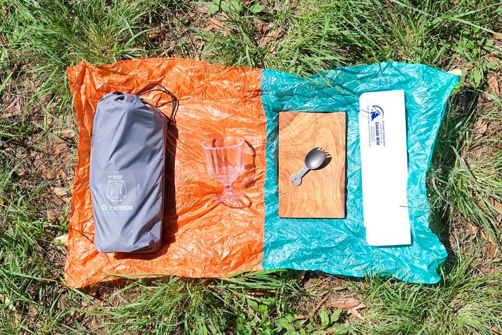 左から、折りたたみ式アウトドアチェア、割れないコップ、カッティングボードとカトラリー、折りたたみ式ミニテーブル。下に敷いてあるのはポケッタブルなレジャーシート