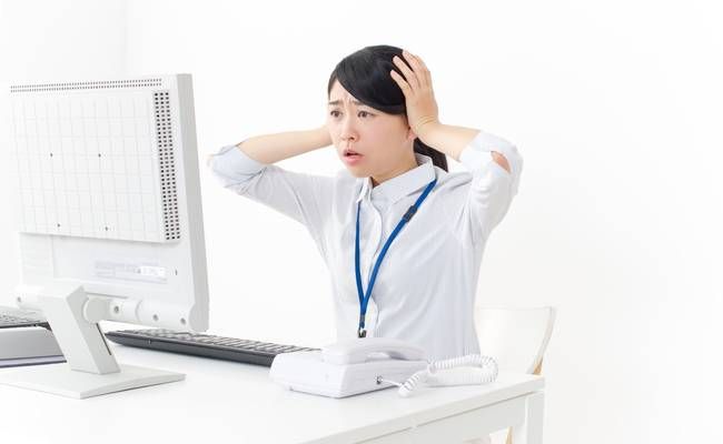 パソコンの前で頭を抱える女性のイメージ
