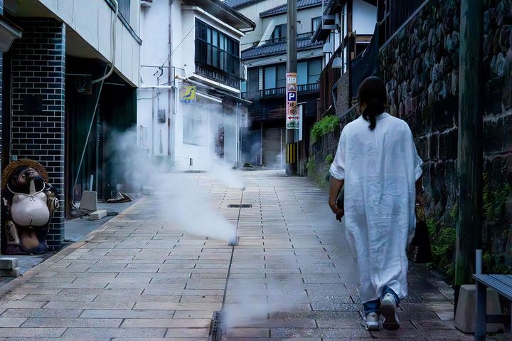 鉄輪温泉街を歩く佳乃子さん。石畳から温泉の湯気がもくもくと立ち上る。歩いているだけで足元からじんわり温まる
