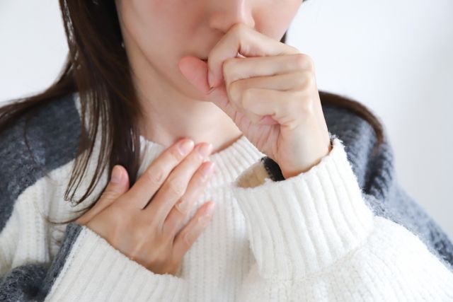 喉を抑えて咳き込む女性