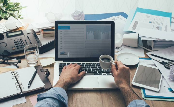 散らかったデスクで仕事する男性の手元