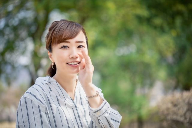 笑顔でこっそり話そうとする女性