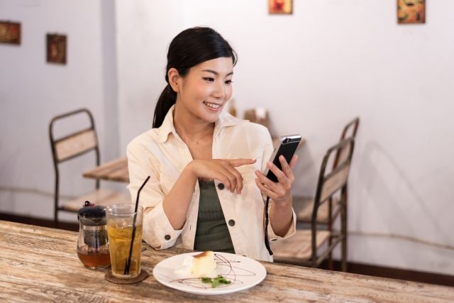 スマホを指さす女性