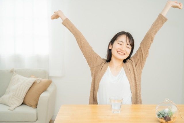 笑顔で伸びする女性