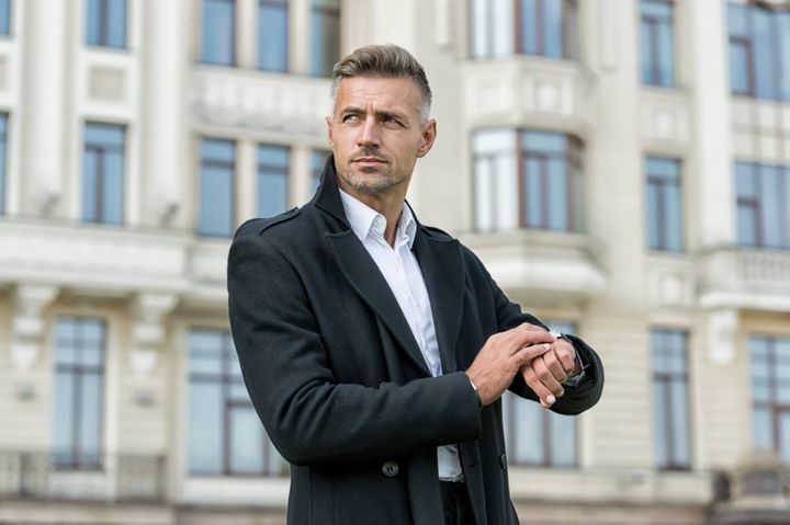 屋外で腕時計を確認する男性