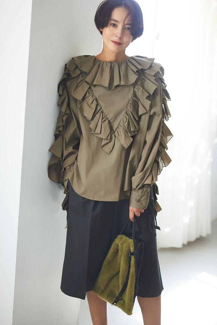 ボリューミーなフリルをたっぷり重ねたデザインが、ミリタリー感を完全に払拭。逆にカーキだからこそ、甘さがトゥーマッチにならずモードっぽく着こなせる。今っぽくてきれいな美シルエットのハーフパンツで引き締めて、エッジィな甘辛ミックスに。ブラウス3万6300円（ミュラー オブ ヨシオクボ） パンツ4万8400円（オブリオ） バッグ3万9600円（ヴァジック／ヴァジックジャパン）