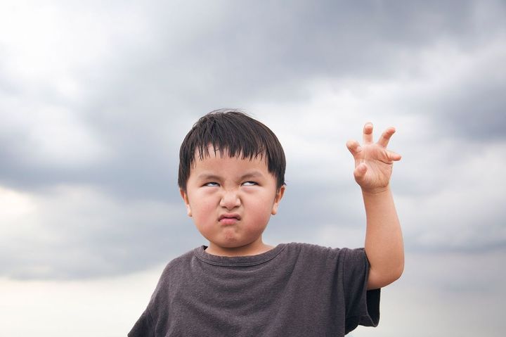 曇り空の下で怖い顔を作る少年