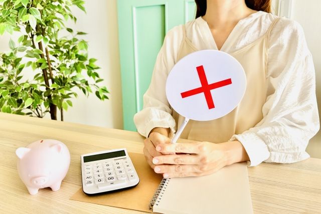 バツの札を持った女性