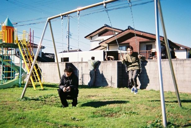 監督、藤井道人の隣でブランコを楽しむ尾上眞秀 [c]2025「港のひかり」製作委員会