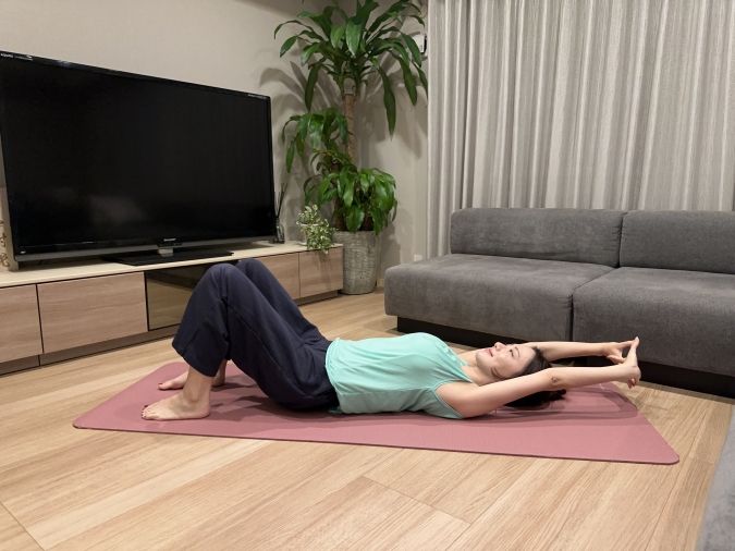 両膝を立て、足は腰幅に開く。両手の指を絡めて、背伸びをする。