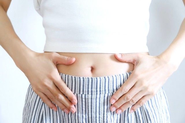 お腹に手を当てる女性