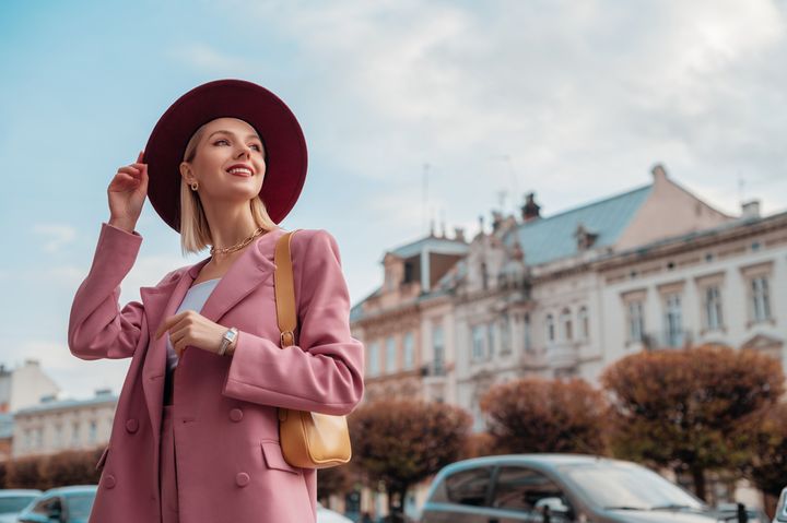 おしゃれな街を歩くピンクのコートの女性