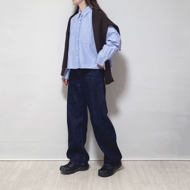 ブラウンのスムースコットンクルーネックセーターを肩がけしているコーデ