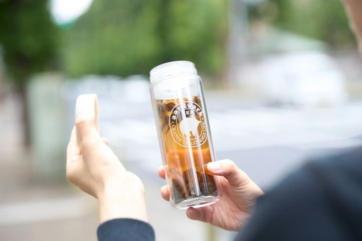 店の外で急須ボトルでお茶を飲む