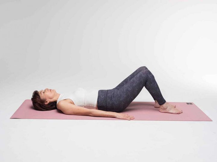 【１】あおむけになり、両ひざを立てます。 両足は腰の幅くらいに開きます。両手を伸ばし体の横におき、手のひらを床に。