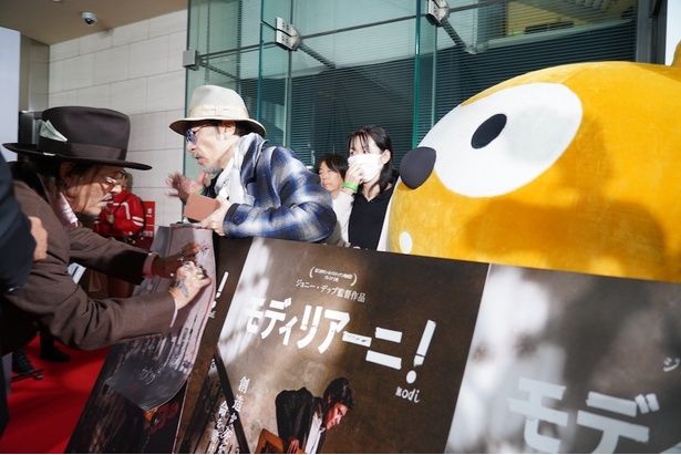 ジョニー・デップがサインをする様子を見つめるポンタ