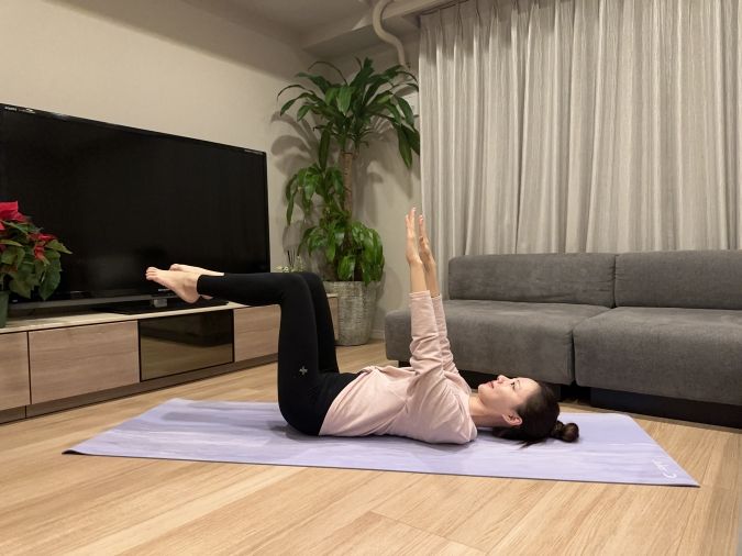 仰向けになり、膝を90度に曲げてテーブルトップ（膝と股関節が90度になる姿勢）をつくる。両腕は天井方向に伸ばし、肩はリラックス。