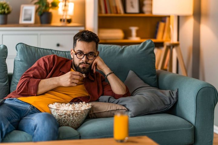 ソファに座りポップコーンを食べている男性