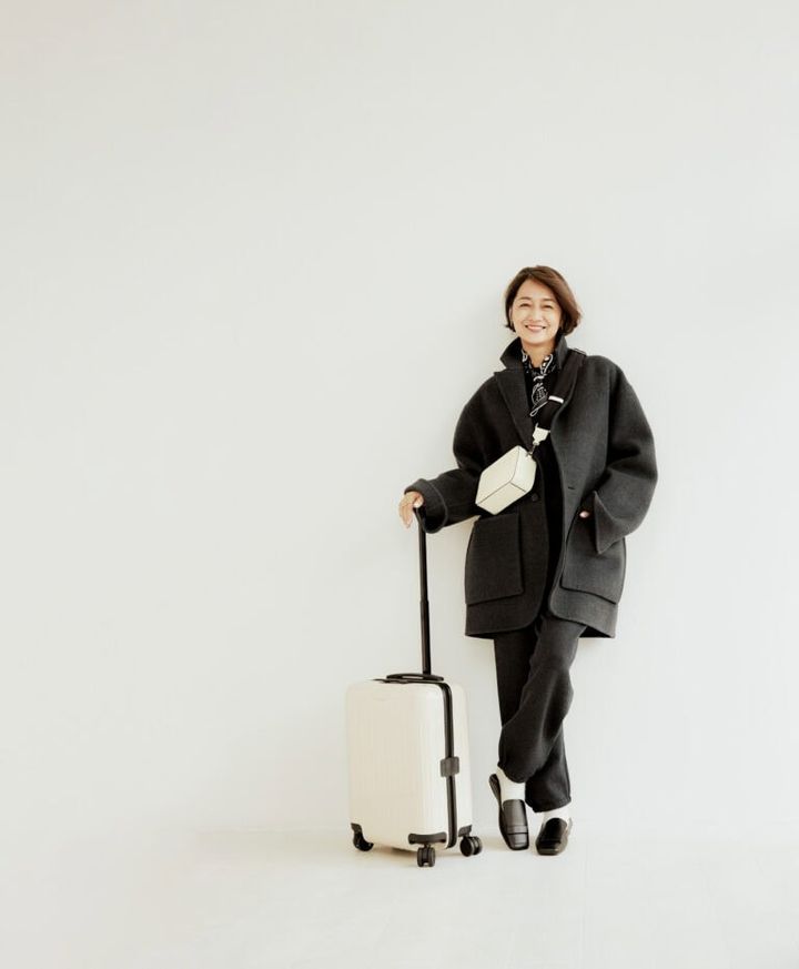 コート¥253,000／ポステレガント、ニット¥27,940、パンツ¥33,990／ともにエイチビューティ＆ユース（エイチ ビューティ＆ユース）、バッグ¥269,500／ヴァレクストラ（ヴァレクストラ・ジャパン）、ピアス¥46,200、リング各¥24,200／すべてヒロタカ（ヒロタカ 表参道ヒルズ）、ソックス¥3,520／マルコモンド（スティーブン アラン シンジュク）、靴¥128,700／セルジオ ロッシ（セルジオ ロッシ ジャパン カスタマーサービス）、スーツケース¥118,800／リモワ（リモワ クライアントサービス）、スカーフ／スタイリスト私物