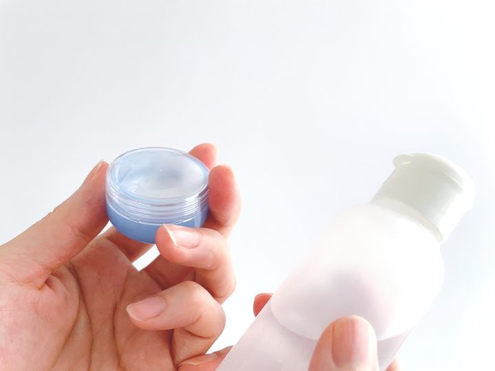 スキンケア用品を見比べる女性の手元