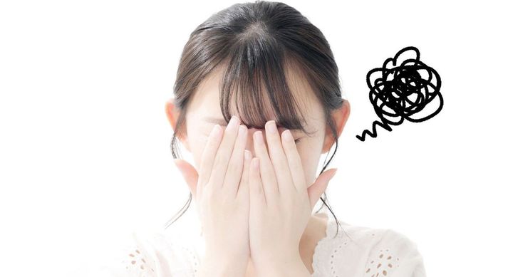 恥ずかしさといたたまれない気持ちで、手で顔を隠している女性