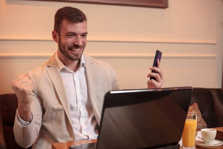 パソコンを見ながらガッツポーズする男性