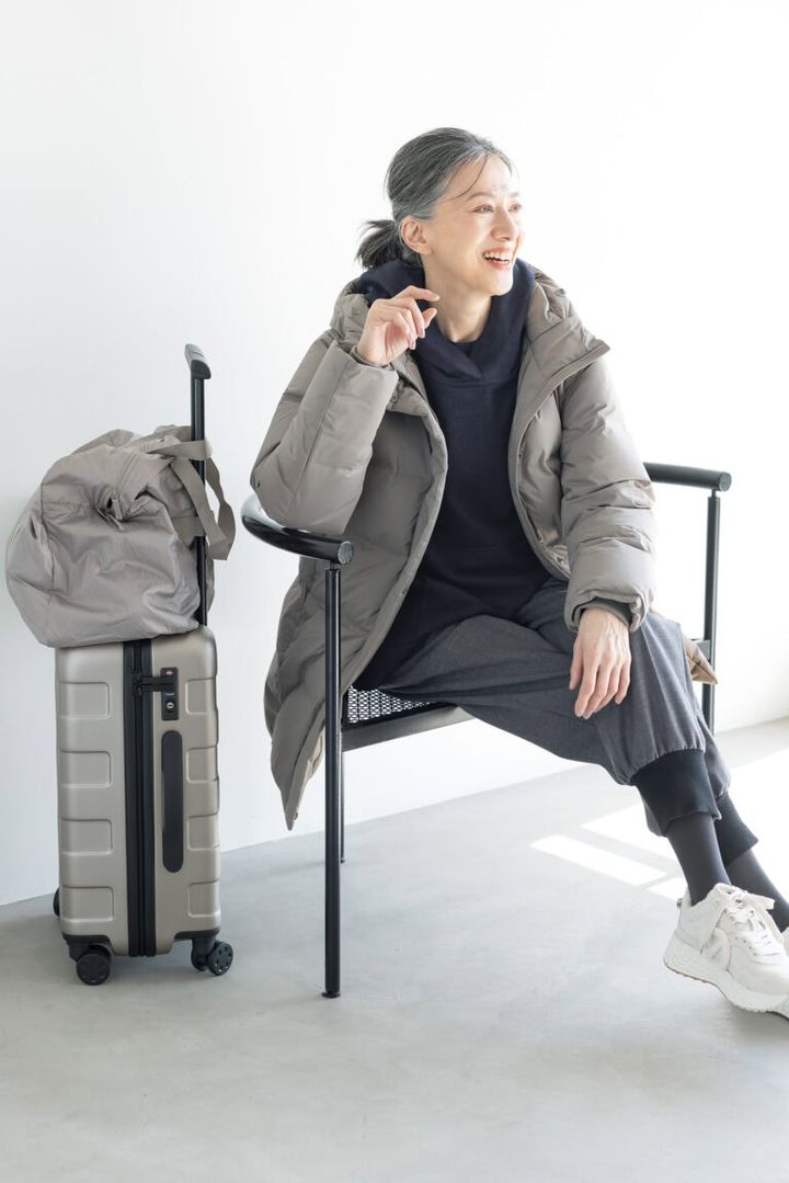 ダウンコート¥17,900／ユニクロ、中に着たクルーネックT¥2,290／ユニクロ：シー（ユニクロ）、ブラウス¥75,900／デ・ドゥエ（アッシュ・ペー・フランス）、パンツ¥47,300／エズミ（リ デザイン）、スニーカー¥35,200／ノーネーム（ストックマン）、ボストンバッグ¥2,990、キャリーケース¥19,900／ともに無印良品（無印良品 銀座）、タイツ／スタイリスト私物